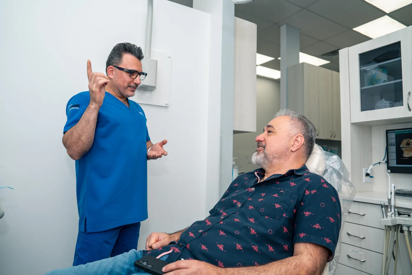 Dr. Bilus Poles talking with a patient about dental implants at Omni Dental in Arlington Heights, IL